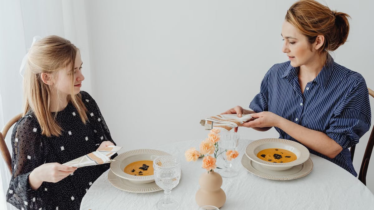 Two women dining with soup at an elegantly set table.
